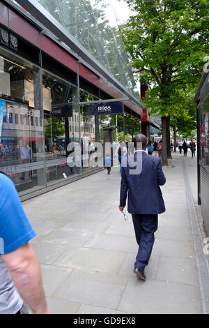 Un imprenditore passeggiate passato un Hugo Boss store nella città di Londra Foto Stock