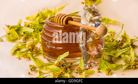 Primo piano della cucchiaia di miele di tiglio e foglie, vaso di cristallo Foto Stock