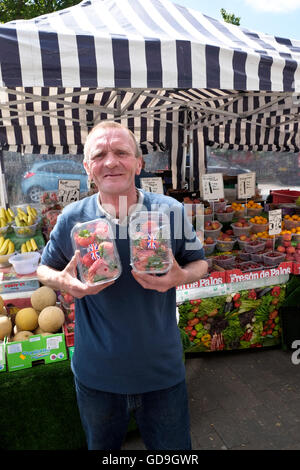 Brentwood REGNO UNITO. Un agricoltore azienda con orgoglio le sue fragole fresche a agricoltori flea bancarelle del mercato stabiliti su un High Street in Brentwood Essex Inghilterra Foto Stock