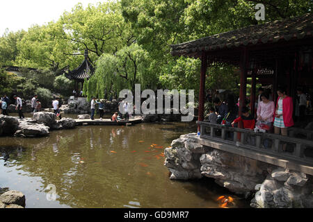 Una casa, uno stagno, oro di pesce, vegetazione, un ponte e turisti nel XVI secolo il Giardino di Yuyuan, un tipico giardino classica. Foto Stock