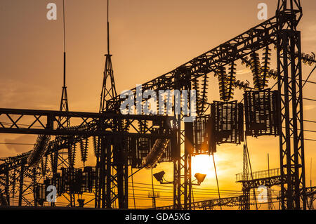 Le linee elettriche, i poli e gli isolatori di vetro in una stazione di alimentazione al tramonto Foto Stock