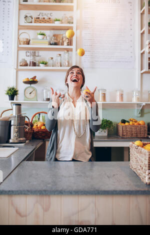 Giovane donna giocoleria con frutti. Felice giovane impiegato femminile giocando con i limoni a juice bar. Foto Stock