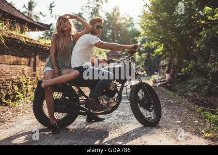 Ritratto di coppia giovane appendere fuori in campagna con il motociclo. Giovane uomo e donna sulla moto. Foto Stock