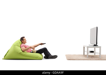 Rilassata uomo seduto su un confortevole beanbag verde e guardare la TV isolato su sfondo bianco Foto Stock