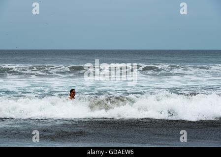 Costa Rica, Guanacaste, Playa Junquillal, Donna galleggianti sotto la pioggia nel mare Foto Stock