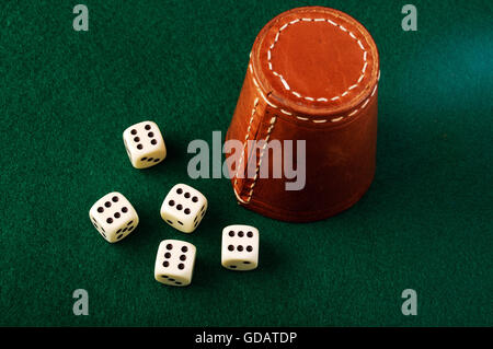 Cinque dadi e cuoio una tazza sul panno verde Foto Stock