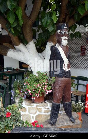 Statua in legno in uniforme di un ex Crètois sulla parte anteriore di un albero. Foto Stock