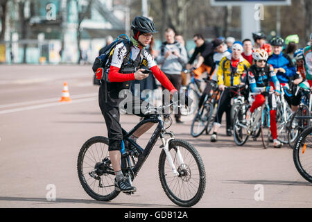 Gomel, Bielorussia - 10 Aprile 2015: giovane ciclista in abbigliamento per il ciclismo utilizza telefono dello smartphone durante la guida Foto Stock