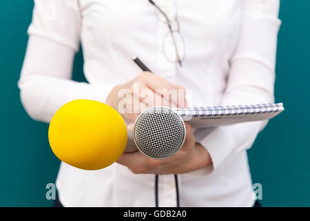Femmina o reporter giornalista a news conferenza, scrivere note, tenendo i microfoni Foto Stock