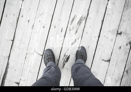 Voce maschile in piedi in scarpe di cuoio stand su bianco molo in legno Piano, prospettiva in prima persona Foto Stock