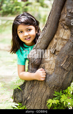 1 indian Kid girl park tronco di albero in piedi a nascondino Foto Stock