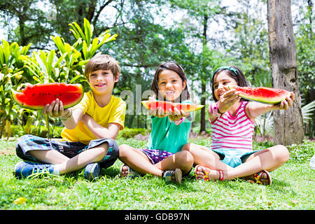 3 bambini indiani amici park mangiando anguria frutti Foto Stock