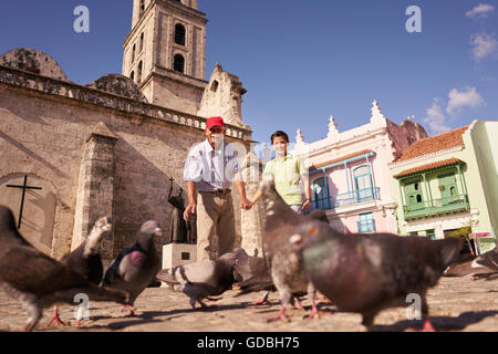 Felici i turisti in vacanza a Cuba. Ispanico persone che viaggiano in Havana. Il nonno e nipote piccioni di alimentazione Foto Stock