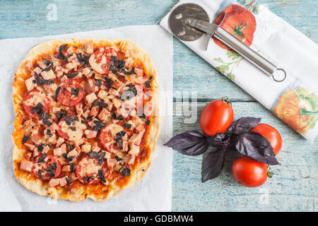 La pizza fatta in casa con salame, i pomodori e le erbe. Foto Stock