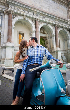 Giovane kissing seduto su uno scooter Vespa. Gianicolo fontana d'acqua. Roma, Italia Foto Stock