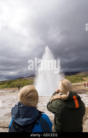 I turisti a guardare Strokkur Geyser che erutta, Geysir, geyser, Islanda, Europa Foto Stock