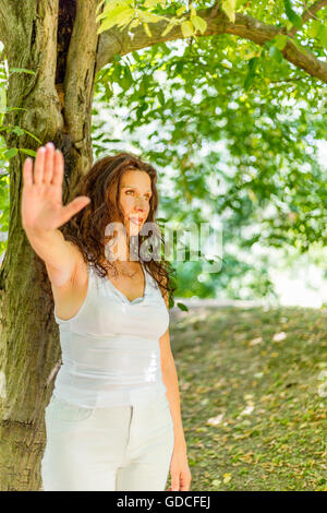 Fermata a parlare con la mia mano gesto da busty elegante donna matura con sentimenti negativi nei confronti di giardino verde con uno sfondo con spazio di copia Foto Stock