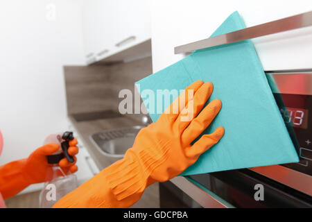 Mano nel guanto di gomma pulisce una nuova cucina. Donna con i lavori domestici, pulizia della cucina. Foto Stock