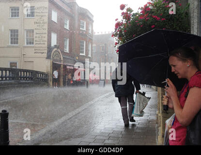 Gli amanti dello shopping si ripara dalla pioggia torrenziale nella cittadina di Newbury, Berkshire, Regno Unito Foto Stock