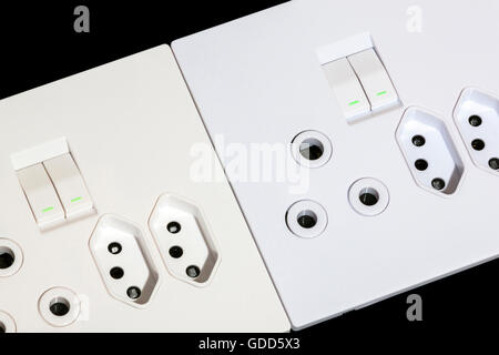 Close up di beige e bianco multiuso per montaggio a parete di prese e interruttori su nero Foto Stock