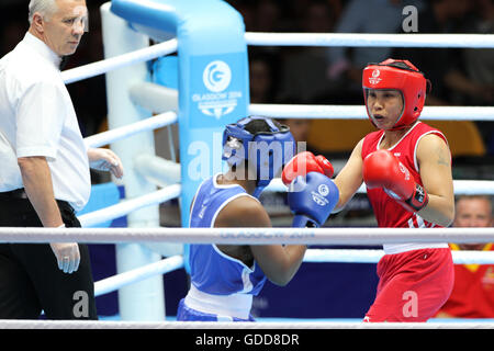 Devi Laishram dell India (rosso) compete contro Maria Machongua del Mozambico (blu) in campo femminile semifinale di peso leggero boxing (57-60kg) Concorrenza al 2014 giochi del Commonwealth a Glasgow. Devi Laishram dell India è andato sul vincere lo scontro. Foto Stock