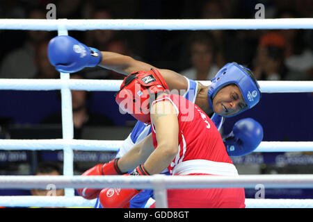 Devi Laishram dell India (rosso) compete contro Maria Machongua del Mozambico (blu) in campo femminile semifinale di peso leggero boxing (57-60kg) Concorrenza al 2014 giochi del Commonwealth a Glasgow. Devi Laishram dell India è andato sul vincere lo scontro. Foto Stock