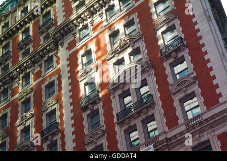 La vista laterale di un arancio e bianco rovinato Manhattan, New York edificio di appartamenti in stile rustico con ornati e design Vittoriano Foto Stock