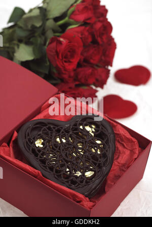 Cuore di cioccolato e rose rosse, presente per il giorno di San Valentino  Foto stock - Alamy