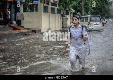 School girl attraversa la strada allagata come piove pesantemente in Jaipur, Rajasthan, India Foto Stock