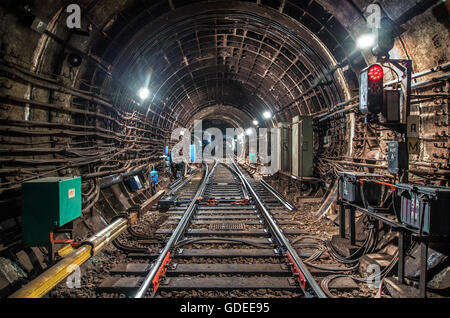 Luce di traffico con un segnale rosso nel tunnel della metropolitana di fronte alla freccia ferroviaria Foto Stock