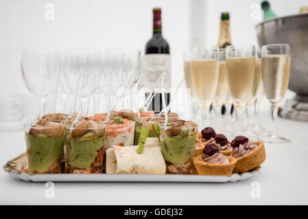 Bicchieri di champagne e una selezione di gustosi petits fours Foto Stock