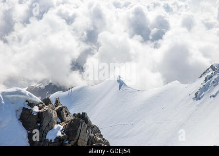 Due persone a piedi lungo la cresta di montagna nelle Alpi svizzere, il Piz Bernina, Grigioni, Svizzera Foto Stock