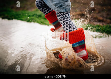 La ragazza del salto nella pozza di fango Foto Stock