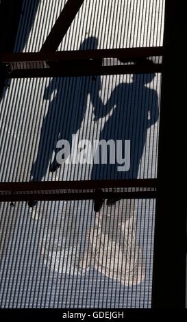 Le ombre di due persone che camminano attraverso un ponte che tiene le mani Foto Stock