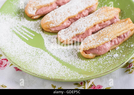 Eclairs con crema di fragole lamponi e zucchero a velo. Foto Stock