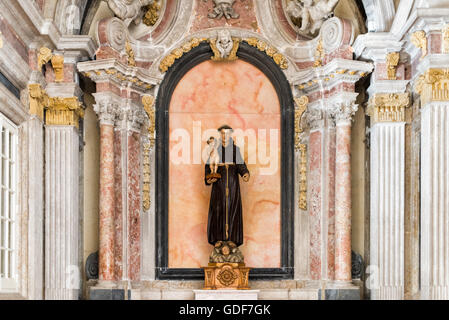 Cappella della Statua di Sant'Antonio Lisbona Portogallo // LISBONA, Portogallo — la Cappella di Sant'Antonio, situata all'interno del Monastero di São Vicente de Fora, è tradizionalmente ritenuta il luogo in cui Sant'Antonio fu internato mentre serviva come canonico regolare di Sant'Agostino. Completata nel 1740, la cappella si distingue per la sua elaborata decorazione in marmo policromo che esemplifica l'artigianato barocco portoghese. Il monastero circostante, costruito nel XVII secolo, si erge come uno dei monumenti religiosi più significativi di Lisbona nel quartiere di Alfama. São Vicente de Fora dispone di numerosi o Foto Stock