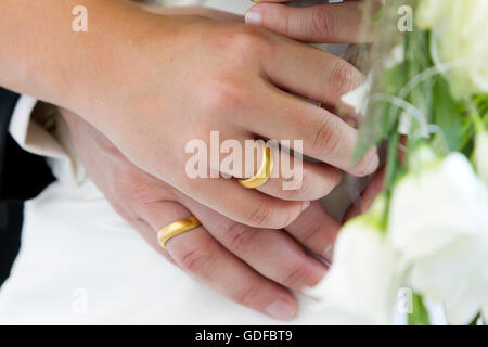 Le mani di una sposa e lo sposo, gli anelli di nozze, bouquet nuziale Foto Stock