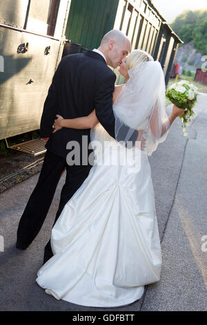 Coppia di sposi in corrispondenza di una stazione ferroviaria, kissing Foto Stock