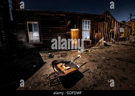 Vecchia carriola con mattoni di fronte a casa in legno Bodie città mineraria California USA Foto Stock