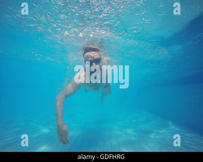 Barba Giovane Uomo con occhiali nuoto sott'acqua nella piscina Foto Stock