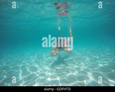 Barba giovane uomo in bicchieri con il pollice in alto le immersioni in acqua pulita azzurra Foto Stock