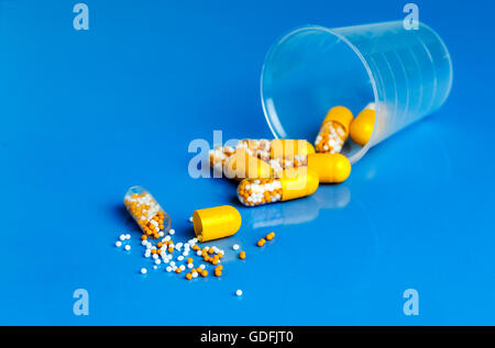 Le capsule di colore giallo con vitamine su uno sfondo blu Foto Stock