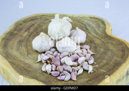 Aglio affettato, spicchio di aglio, sul blocco di spacco sul vintage sfondo di legno Foto Stock
