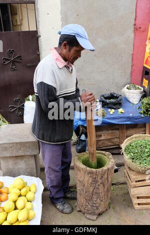 L'uomo pounding erbe per rendere la salsa locale nel mercato Analakely, Antananarivo, Madagascar. Foto Stock