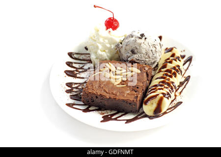 Brownie al cioccolato con gelato alla banana e ciliegia sulla cima isolata su sfondo bianco Foto Stock