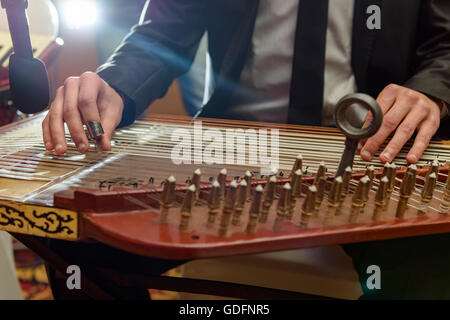 Musicista giocando Arabian Qanon strumento musicale durante una sinfonia Foto Stock