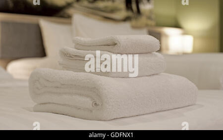 Asciugamani Bianchi e laminati impilati sul letto Foto Stock