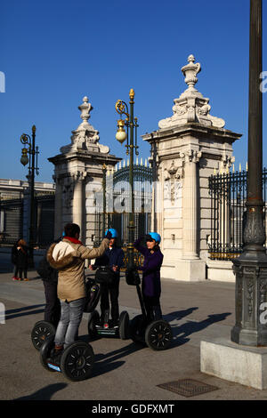 Turisti asiatici su Segway Tour nella parte anteriore del gateway principale del Palazzo Reale, a Plaza de la Armeria, Madrid, Spagna Foto Stock