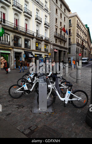 Uomo di noleggiare un BiciMAD bicicletta elettrica in corrispondenza di una stazione di aggancio sulla Plaza Puerta del Sol di Madrid, Spagna Foto Stock