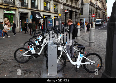 Uomo di noleggiare un BiciMAD bicicletta elettrica in corrispondenza di una stazione di aggancio sulla Plaza Puerta del Sol di Madrid, Spagna Foto Stock